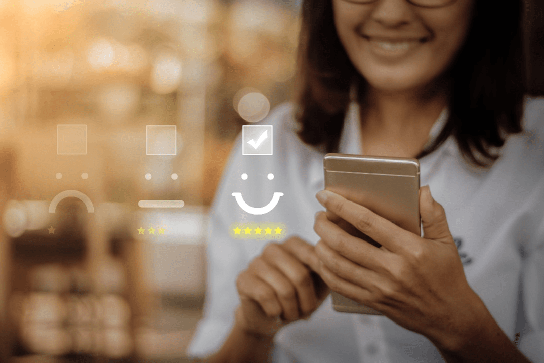 Stock image of a smiling person on their phone rating something five stars.