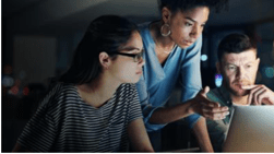 Stock photo of three co-workers gathered around a computer screen.